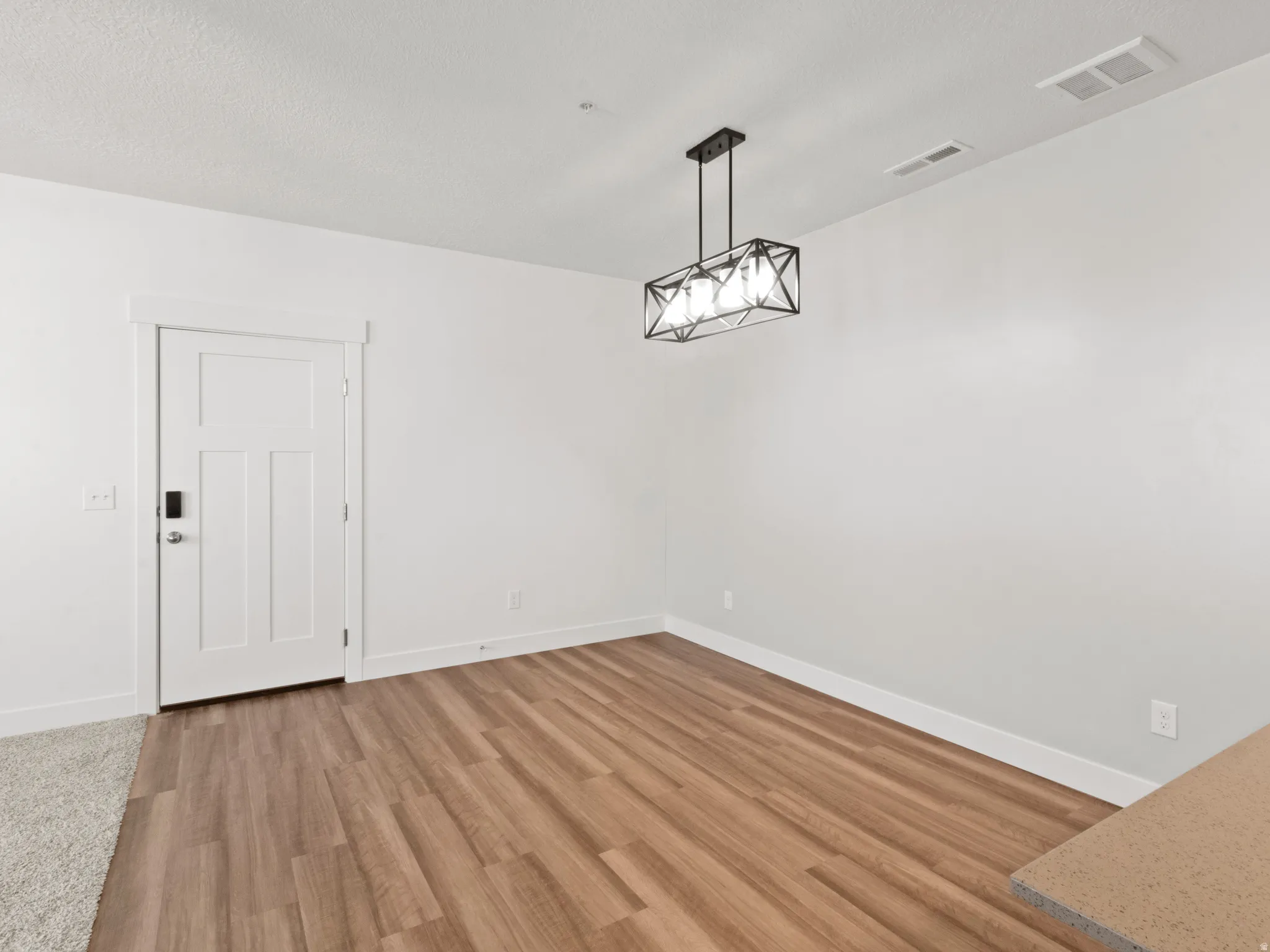 Unfurnished dining area featuring light wood-type flooring and a textured ceiling