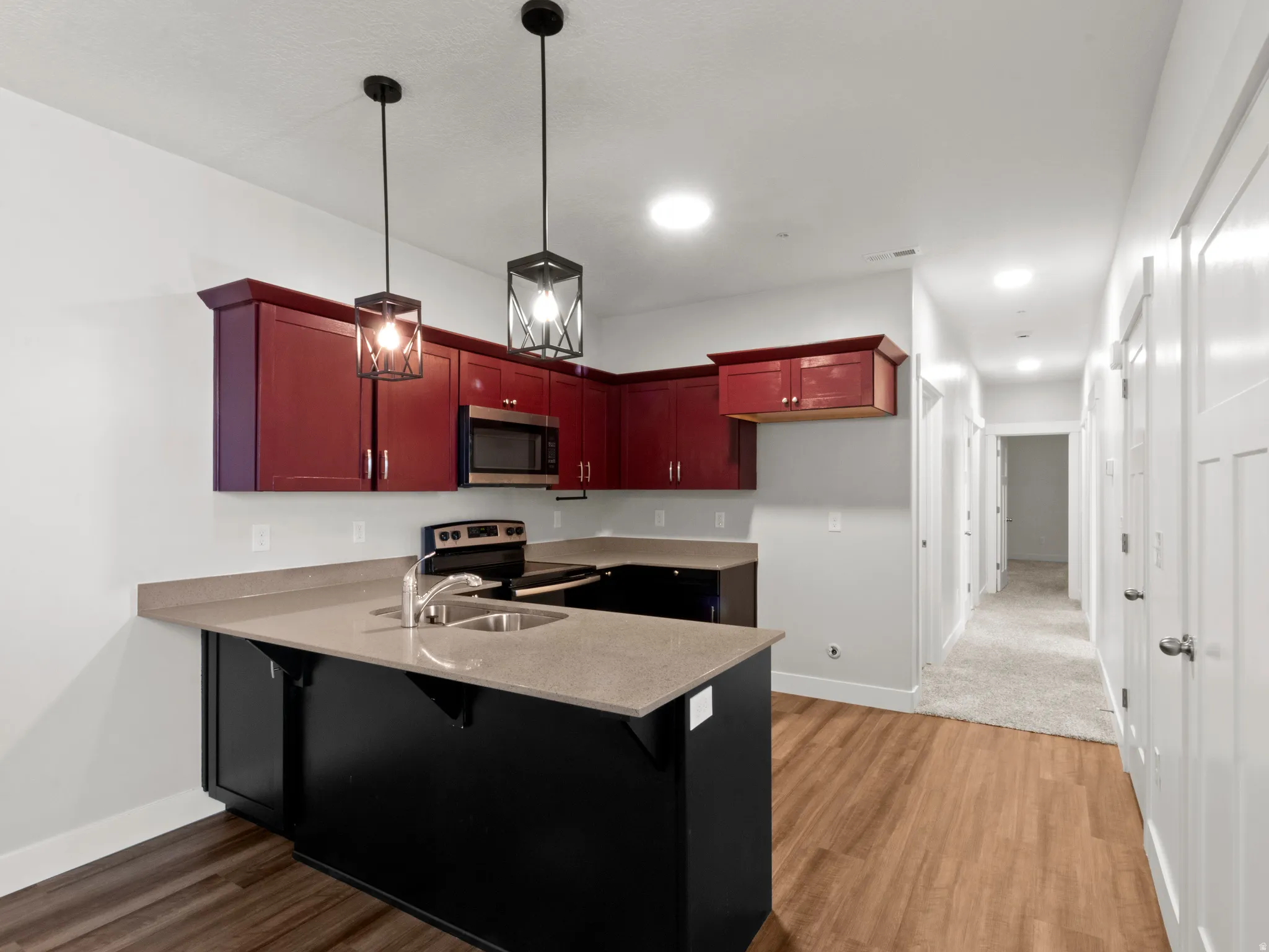 Kitchen featuring hanging light fixtures, appliances with stainless steel finishes, a kitchen breakfast bar, and light wood-style floors