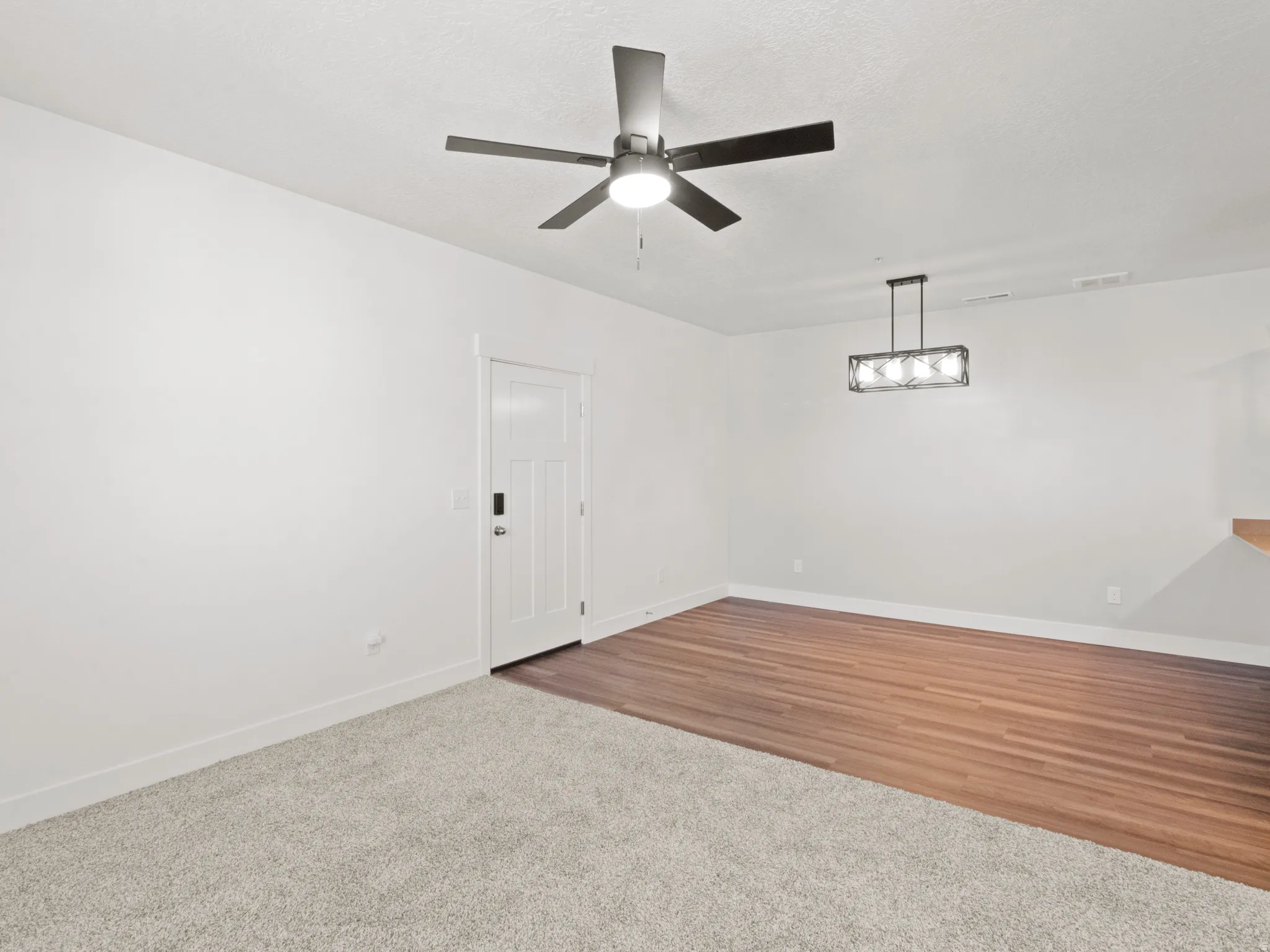 Unfurnished room with carpet, a ceiling fan, and wood finished floors