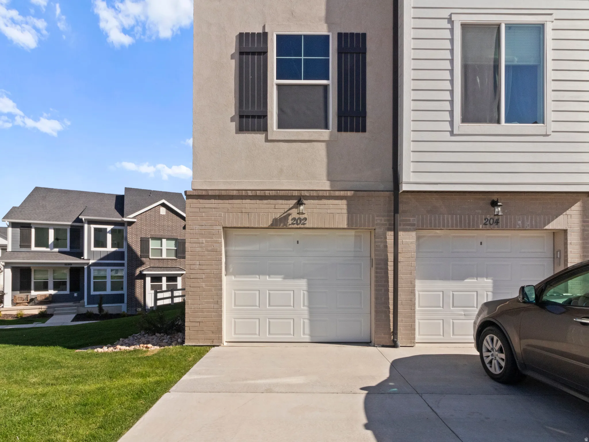 View of property exterior featuring brick siding, concrete driveway, a garage, and a lawn