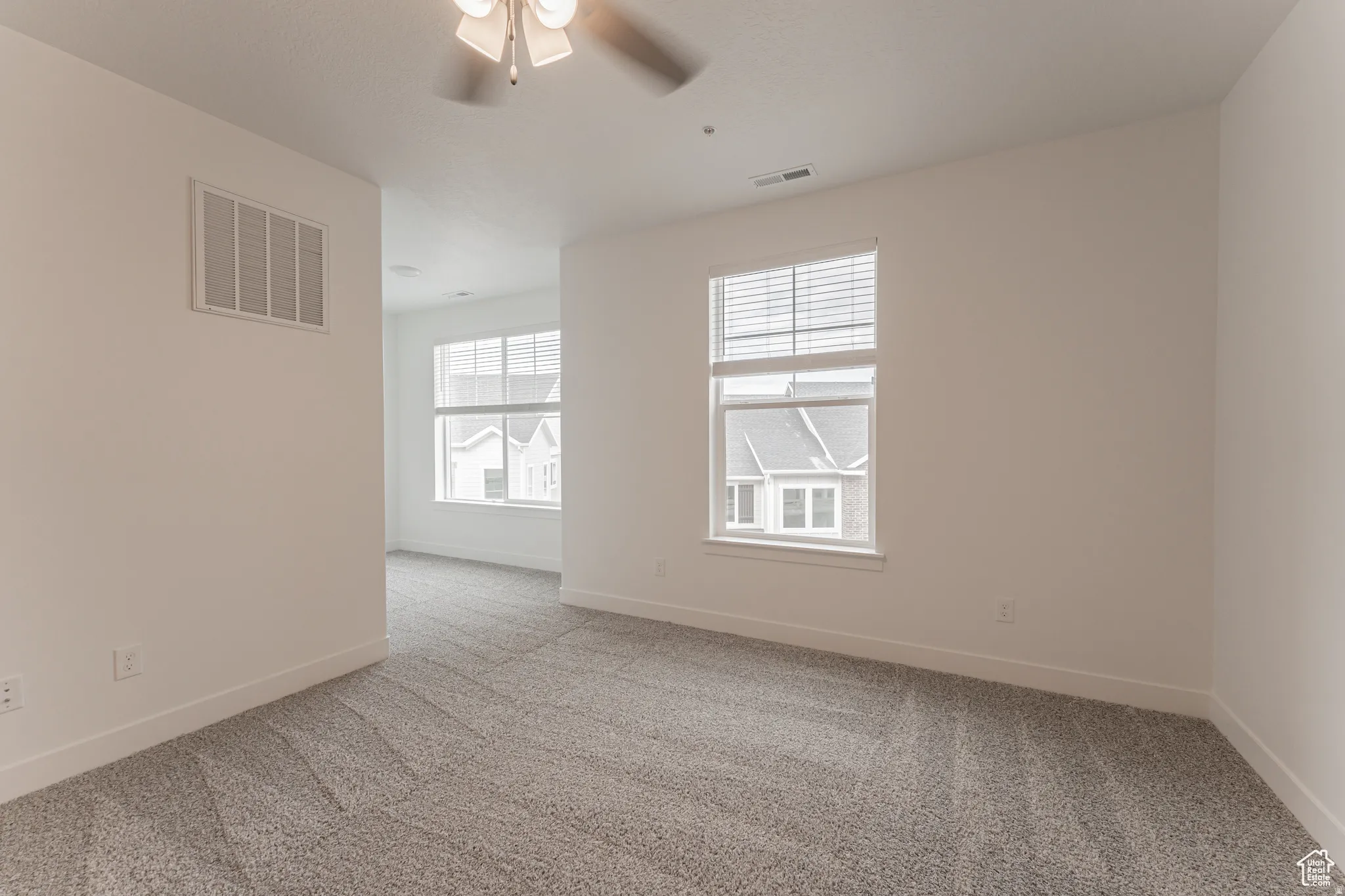Unfurnished room featuring light carpet and a ceiling fan