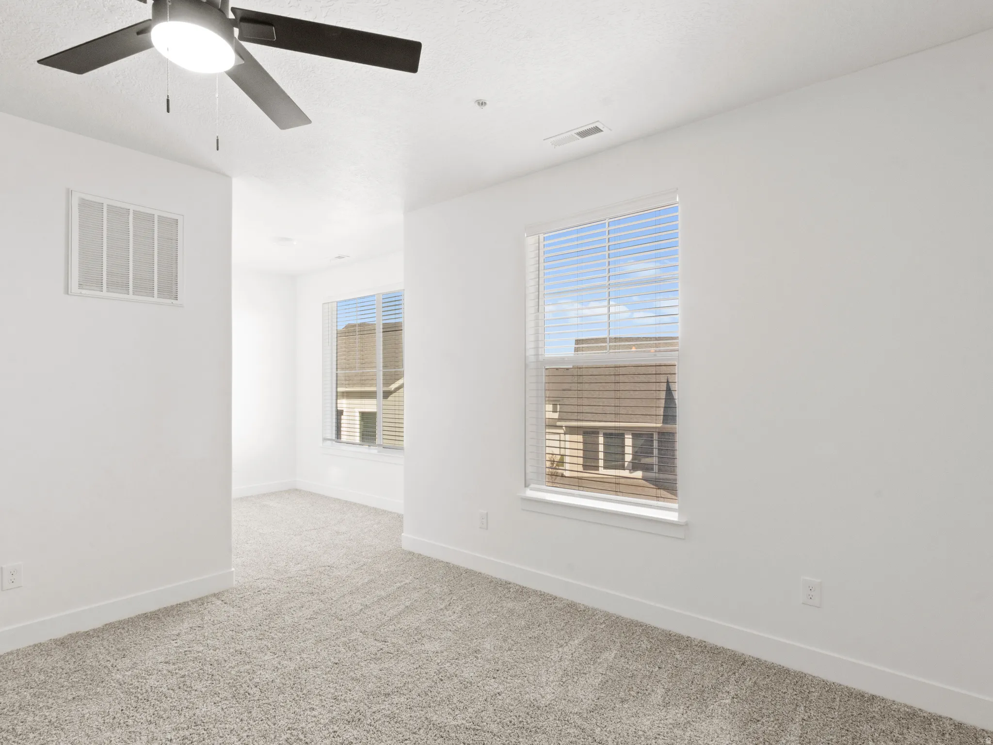 Spare room with light colored carpet, ceiling fan, and a textured ceiling