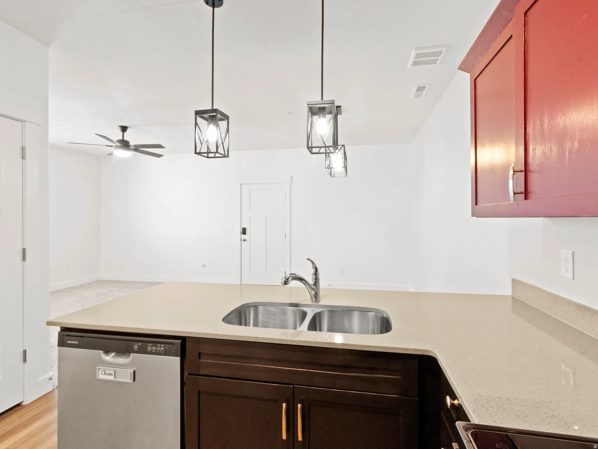 Kitchen featuring stainless steel dishwasher, hanging light fixtures, light stone counters, a peninsula, and open floor plan