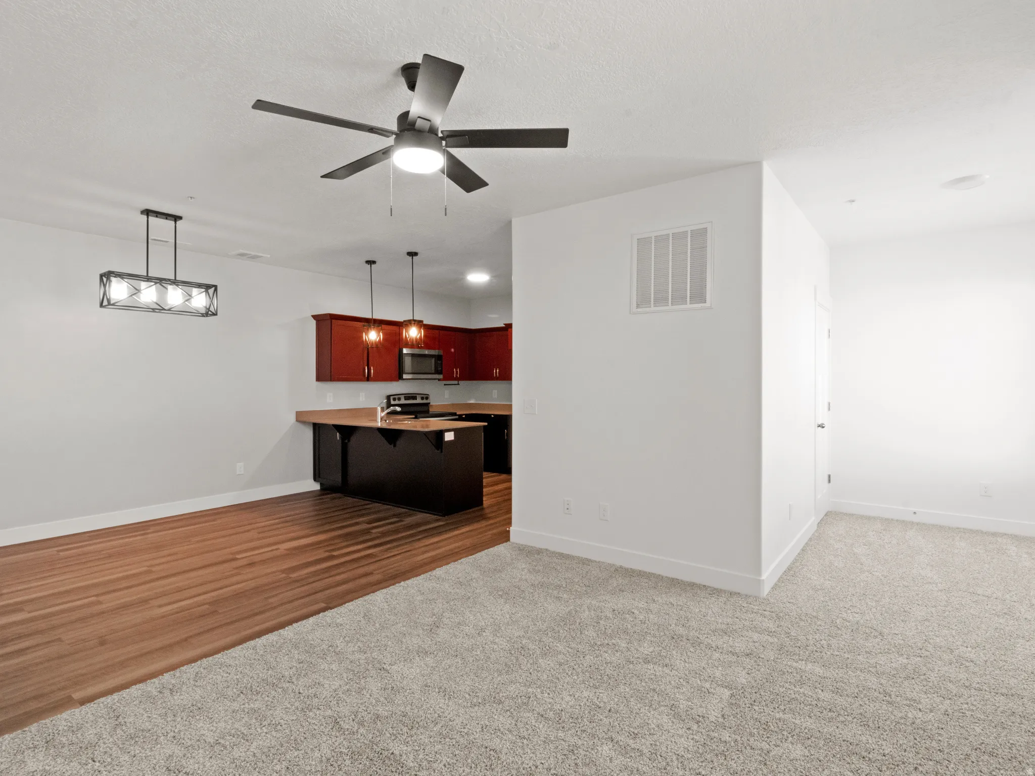 Unfurnished living room with dark carpet and a ceiling fan
