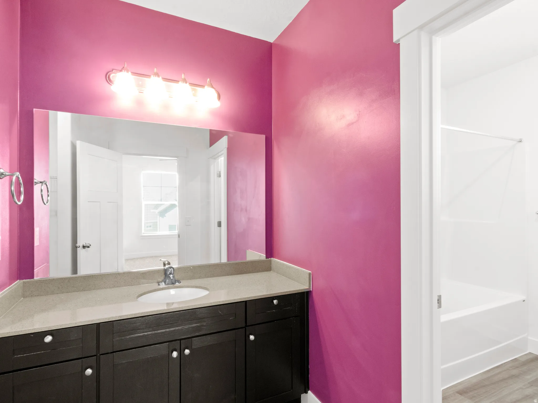 Bathroom featuring vanity, tub / shower combination, and wood finished floors