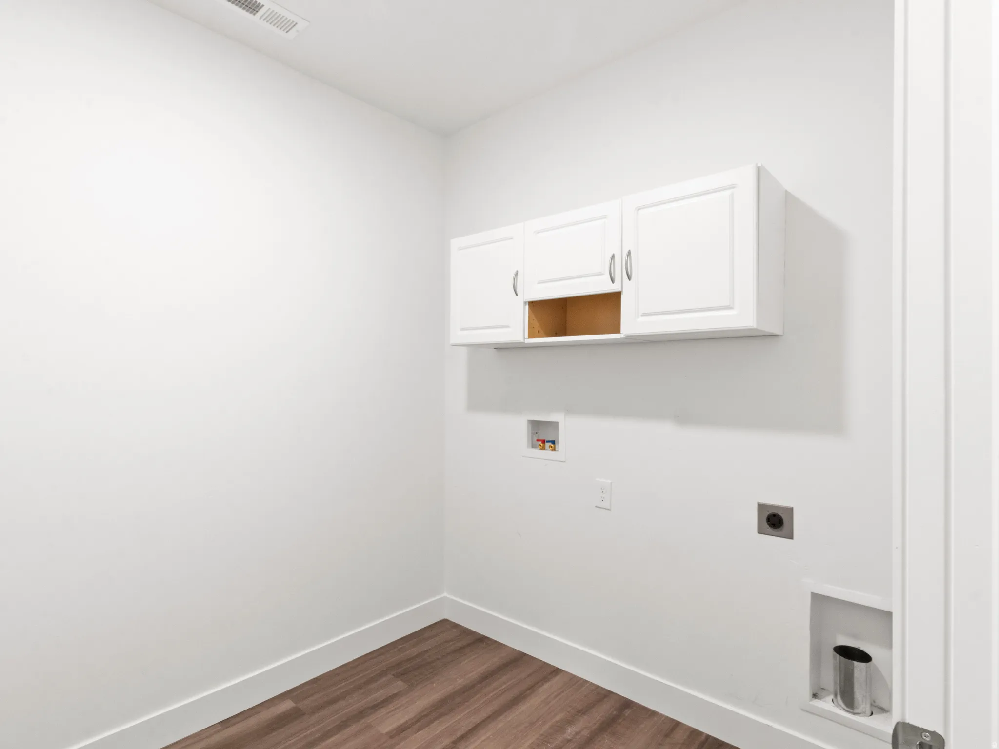 Washroom featuring washer hookup, cabinet space, dark wood-type flooring, and hookup for an electric dryer