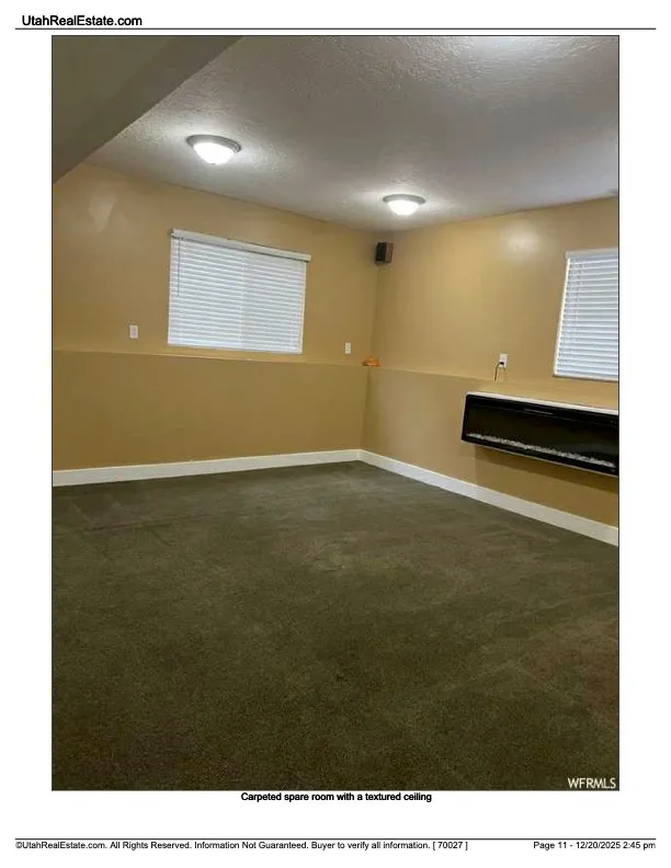 Empty room with a textured ceiling and dark carpet