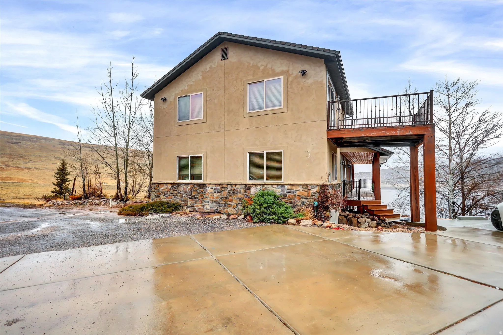 Back of house with stucco siding, stone siding, and a patio