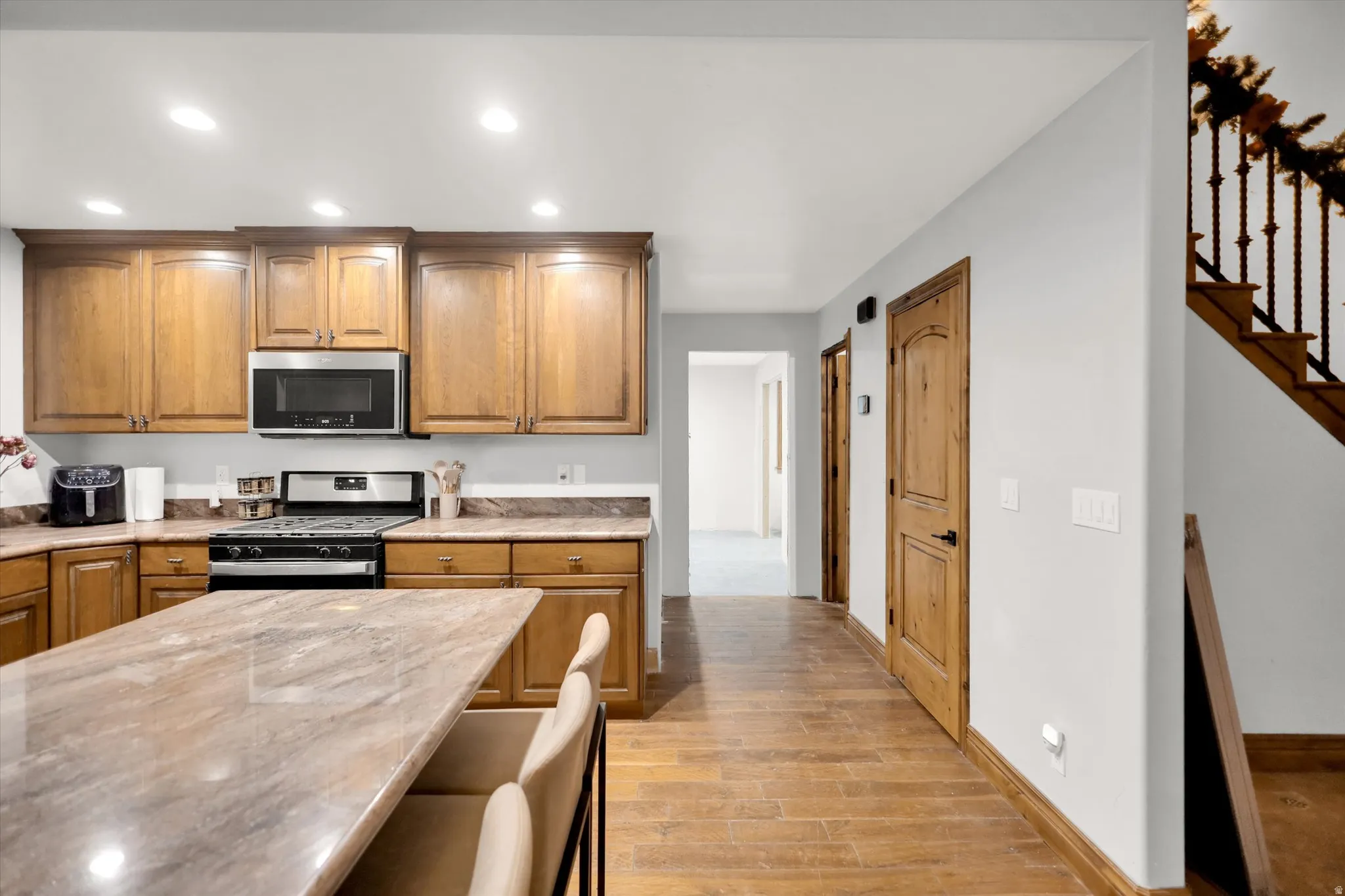 Kitchen with appliances with stainless steel finishes, recessed lighting, brown cabinets, light wood-style flooring, and a breakfast bar