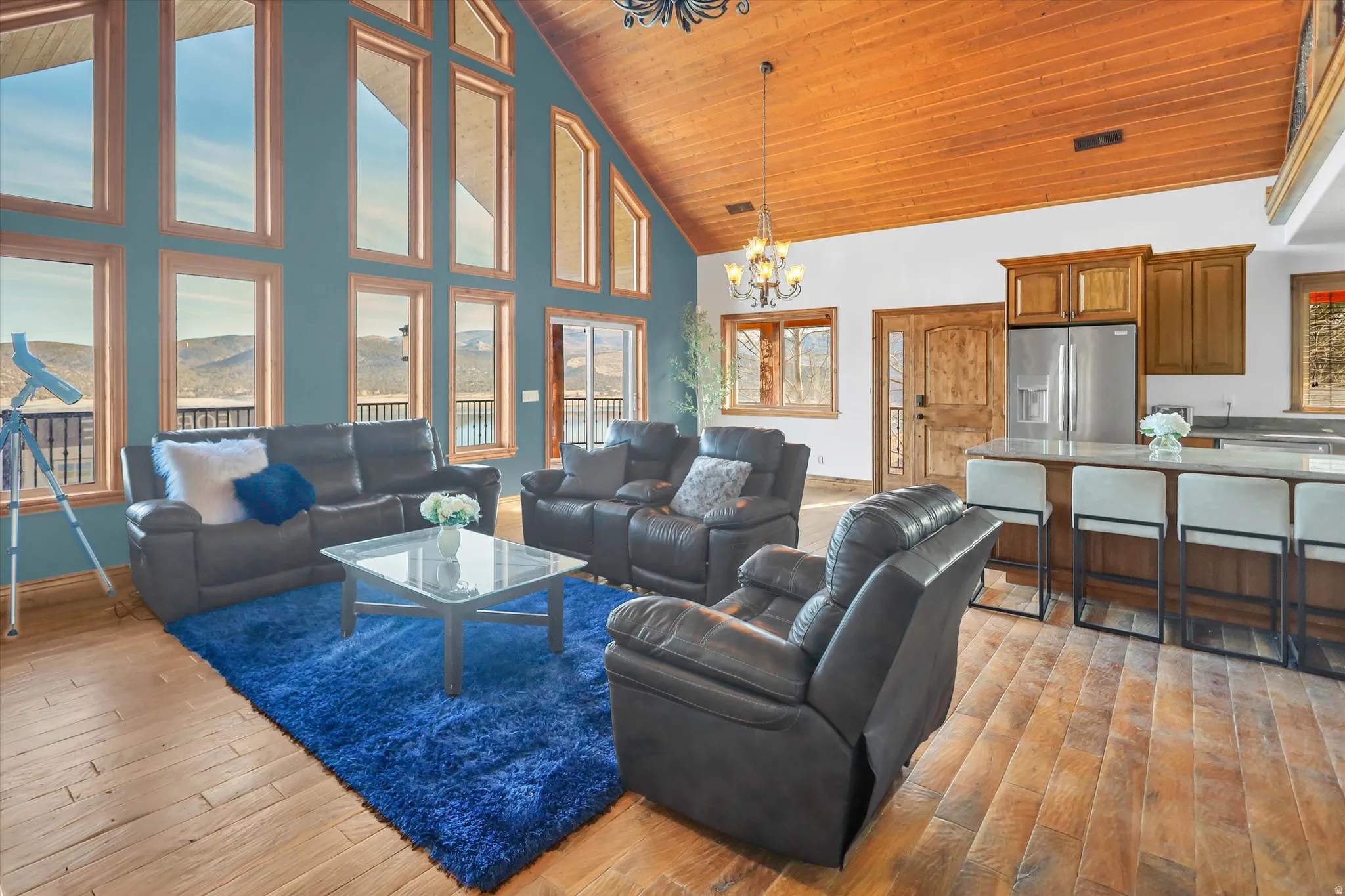 Living area featuring suspended lighting, light wood-style flooring, and a high wood ceiling