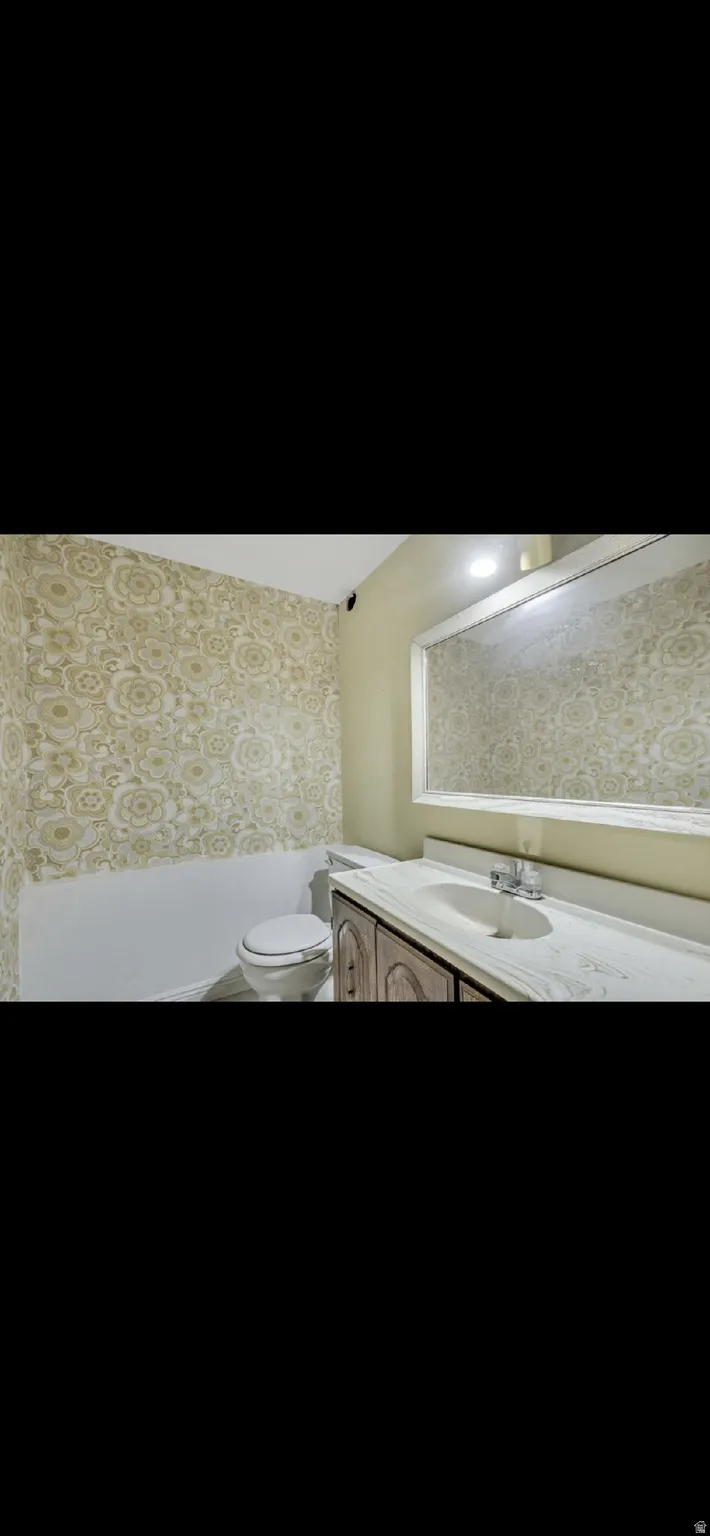 Bathroom with wallpapered walls and vanity