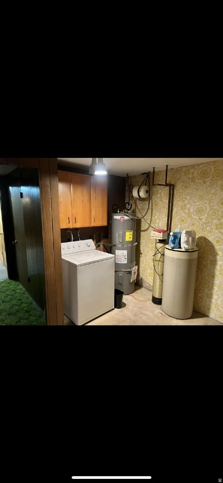 Laundry room featuring washer / dryer, water heater, wallpapered walls, and cabinet space