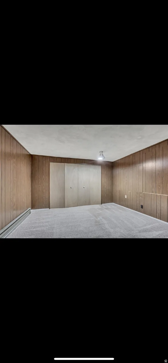 Misc room featuring wood walls and a baseboard heating unit