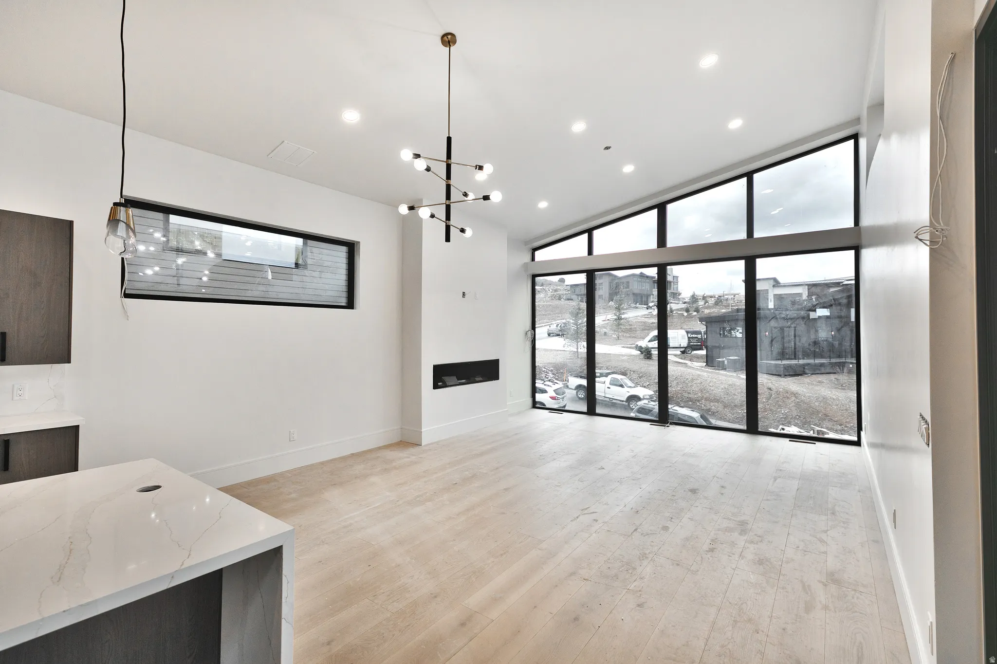 living room featuring a chandelier, expansive windows, fireplace, recessed lighting, and light wood-style floors. Will have beams on the vaulted ceiling.