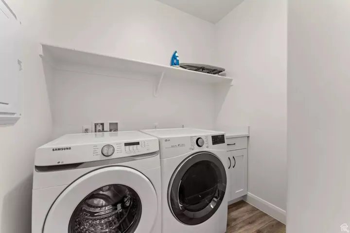 Laundry room featuring washing machine and clothes dryer, cabinet space, and light wood finished floors