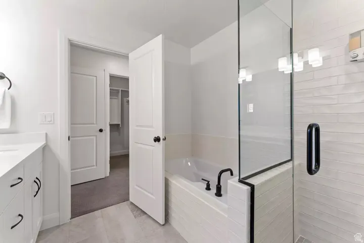 Bathroom with vanity, a bath, a stall shower, and a walk in closet