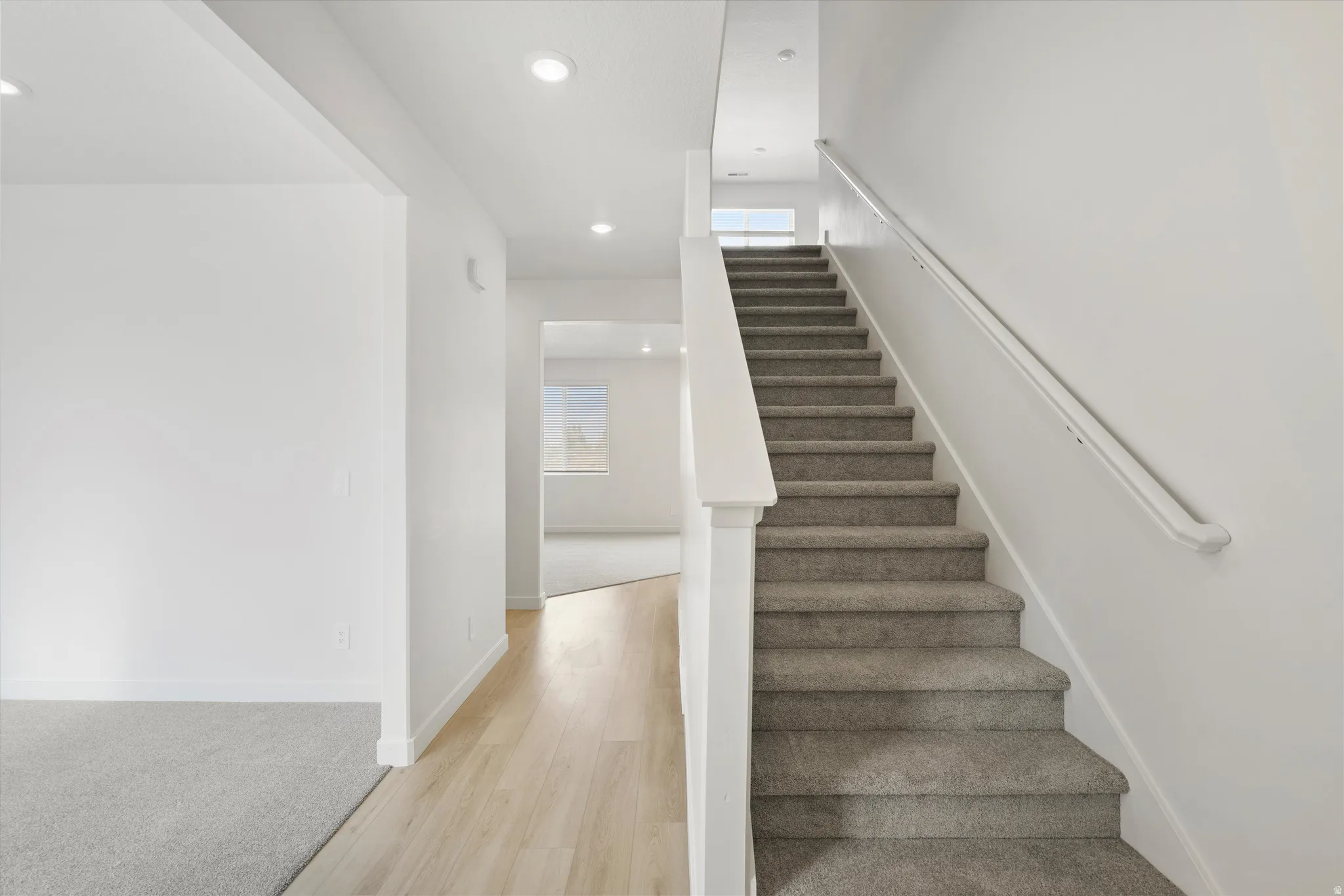 **DISCLAIMER** Interior colors & finishes may vary.Staircase with plenty of natural light, wood finished floors, recessed lighting, and carpet floors