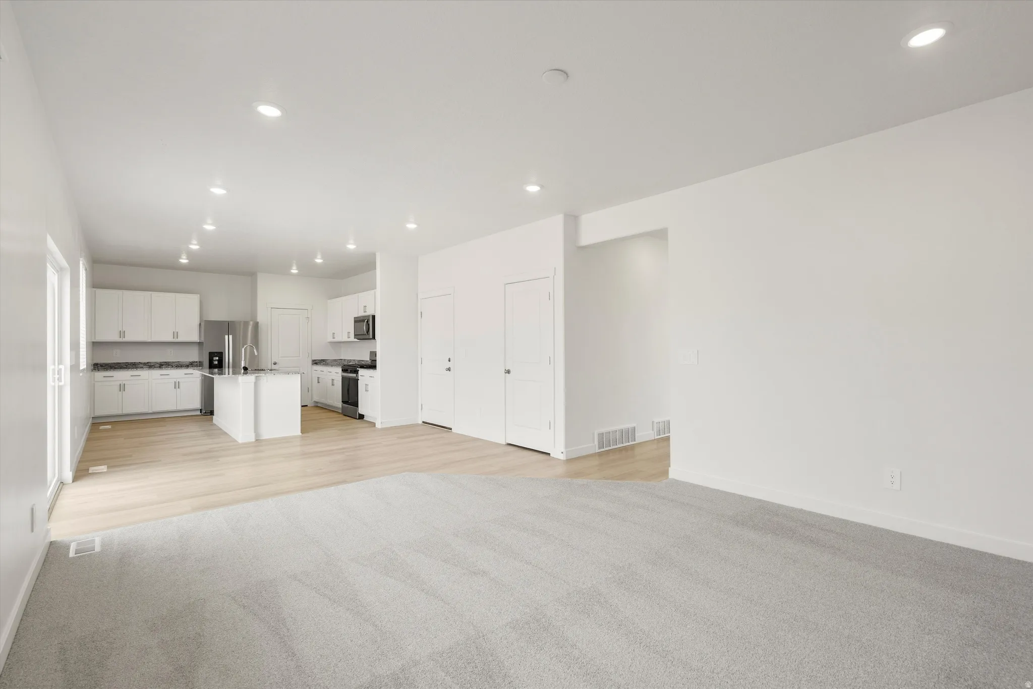 **DISCLAIMER** Interior colors & finishes may vary.Unfurnished living room featuring light colored carpet and recessed lighting