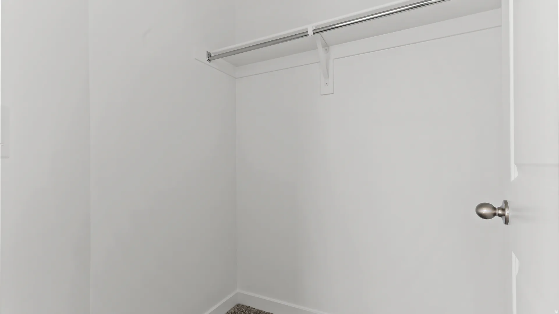 Closet interior featuring a chrome hanging rod and a high shelf