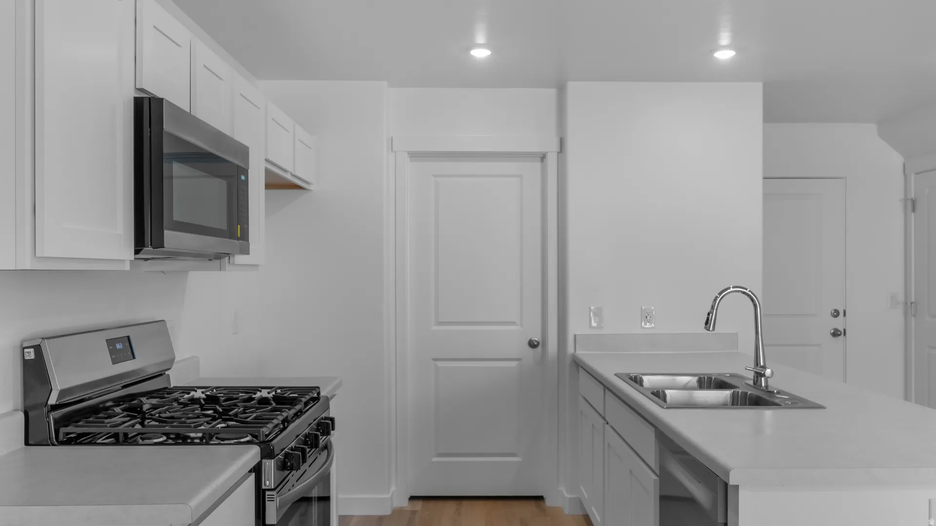 Modern kitchen featuring white shaker cabinetry, stainless steel gas range, coordinating microwave, and a double basin sink with a gooseneck faucet