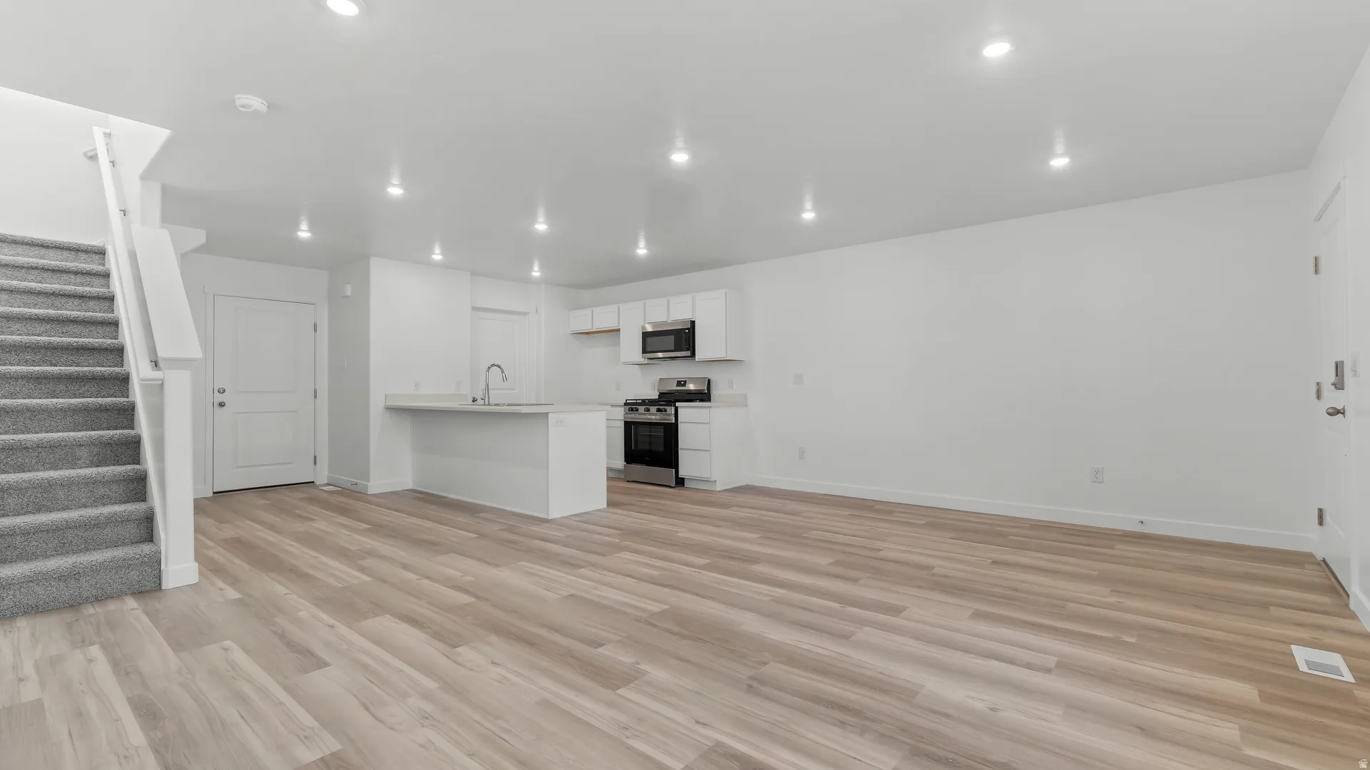 Open-concept living area featuring wood-finish flooring, recessed lighting, and white walls