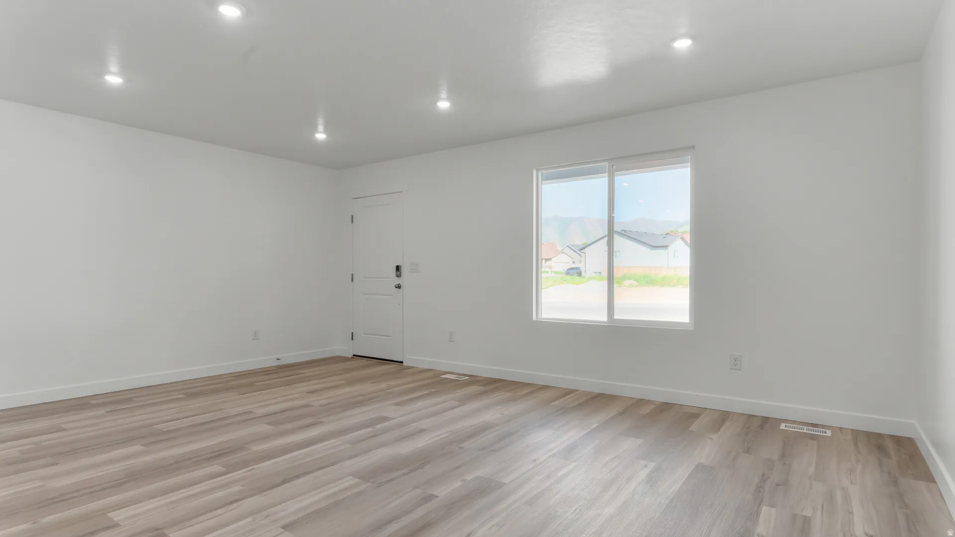 Bright interior space featuring wood-finish flooring, recessed lighting, and a white paneled door