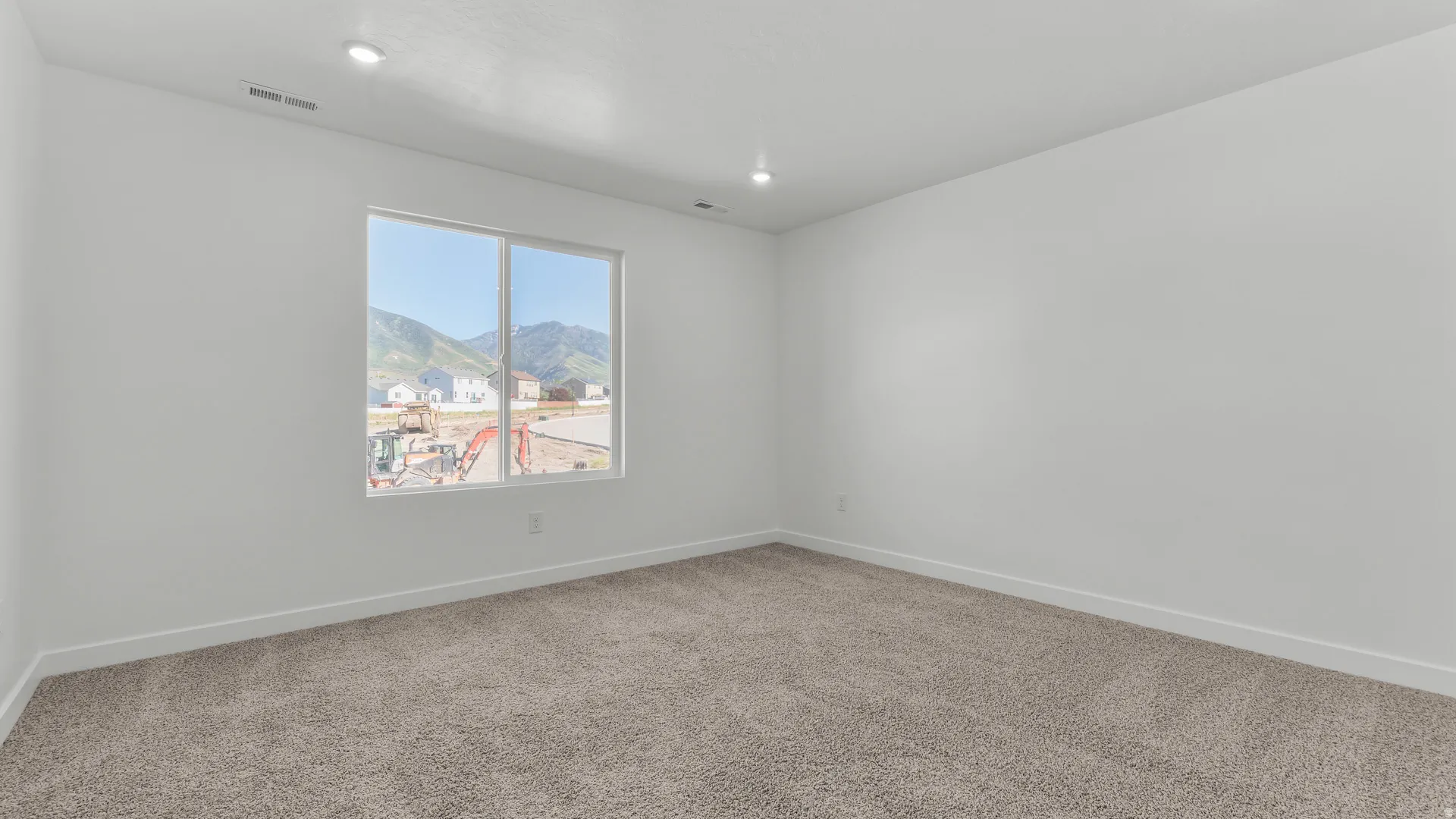 Spacious room with plush carpet flooring and a large window offering mountain scenery