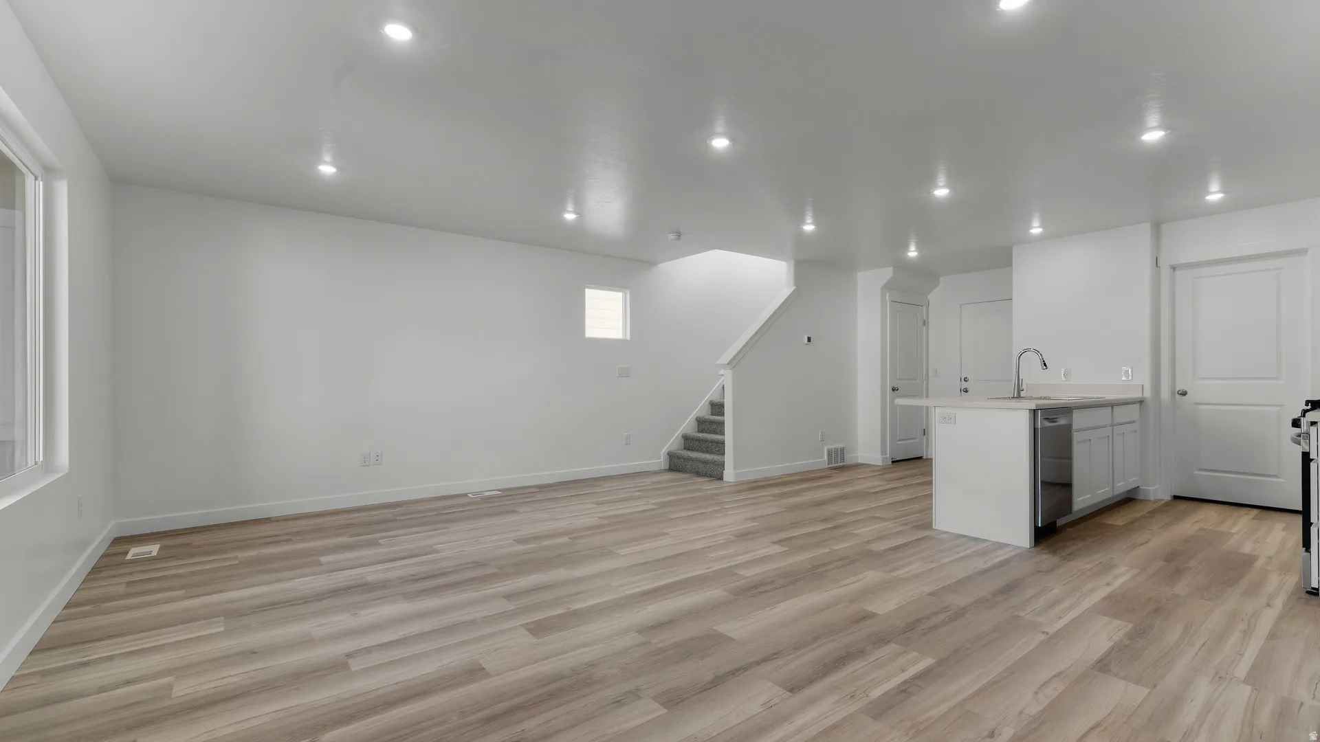 Open-concept living area featuring wood-finish flooring, recessed lighting, and a kitchen island with integrated sink