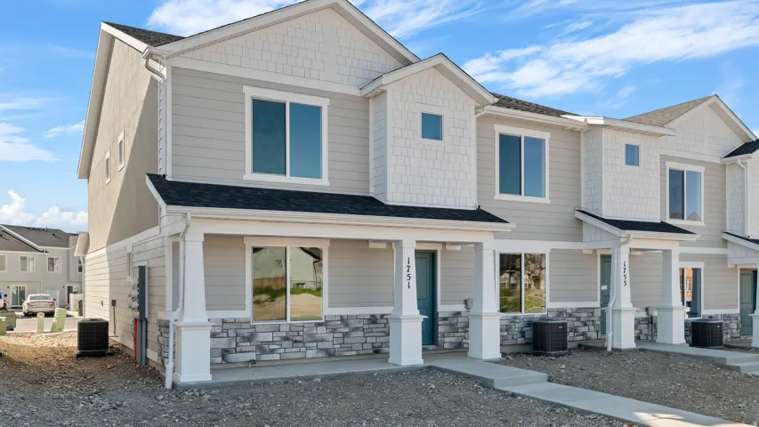 New construction townhome featuring a multi-textured facade with horizontal siding, shingle accents, and stone veneer detailing