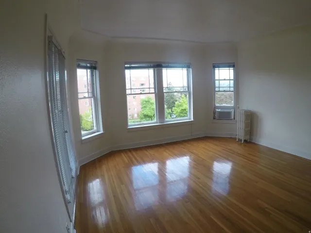 Apt # 4 >  Unfurnished room featuring wood finished floors and radiator heating unit