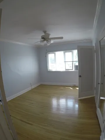 Apt # 15 > Unfurnished room with ornamental molding, light wood finished floors, and a ceiling fan