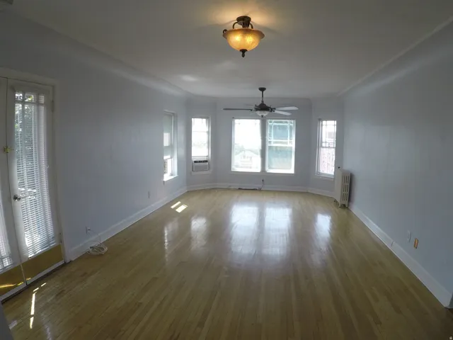 Apt # 15 > Unfurnished dining area featuring wood-type flooring, healthy amount of natural light, and radiator