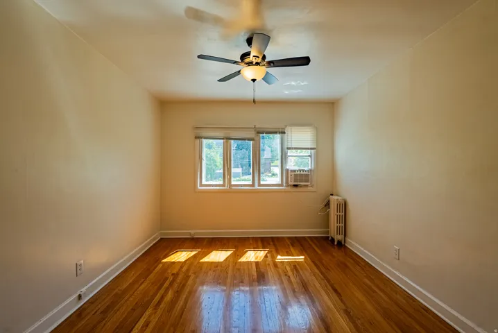Spacious room featuring wood-finish flooring, white baseboards, and neutral wall tones