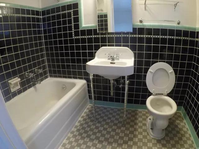 Apt # 4 >  Full bathroom featuring tile walls, dark tile patterned floors, shower / washtub combination, and a wainscoted wall