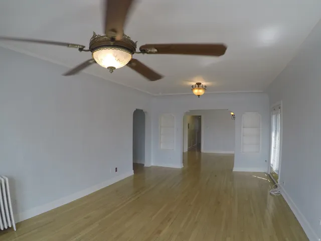 Apt # 15 > Spare room featuring arched walkways, radiator heating unit, light wood finished floors, and built in features