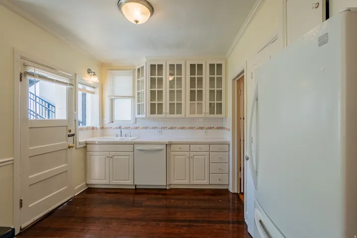 Kitchen featuring white cabinetry, glass-front upper cabinets, white tile countertops, and dark wood-finish flooring