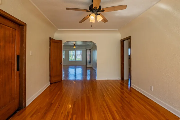 Rich wood-finish flooring extends through an arched doorway into additional living space