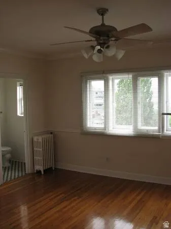 Apt # 8 > Empty room with crown molding, radiator, dark wood-style floors, and healthy amount of natural light