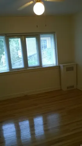 Apt # 1 Empty room with dark wood-style flooring, a ceiling fan, and radiator heating unit