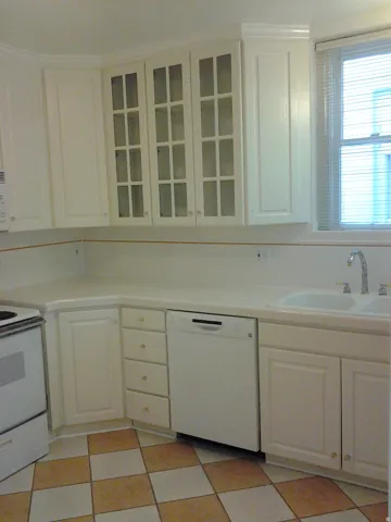 Apt #2 >  Kitchen with light flooring, white appliances, and white cabinets