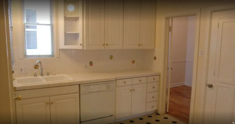 Apt # 5 >  Kitchen featuring dishwasher, tile counters, white cabinetry, and tasteful backsplash
