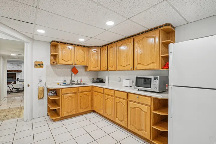 Kitchen featuring open shelves, white appliances, light countertops, a paneled ceiling, and recessed lighting