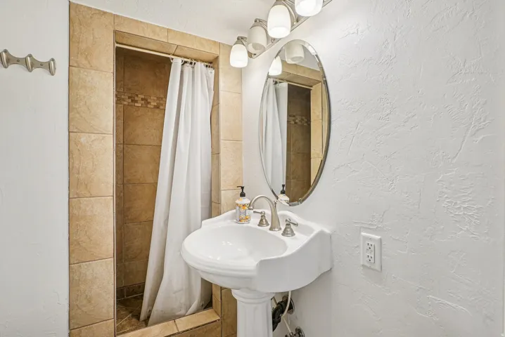 Full bath featuring a textured wall and a shower stall