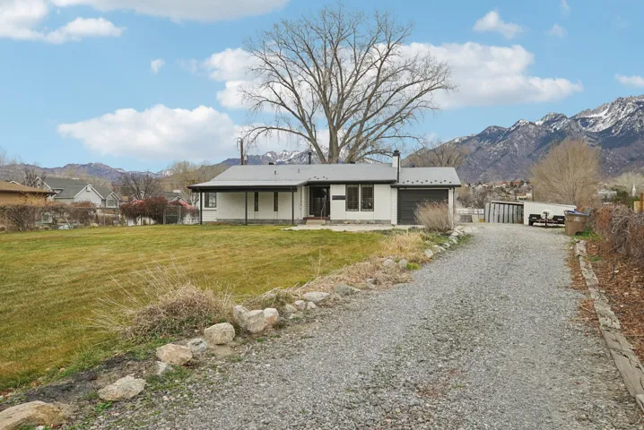Ranch-style home featuring a mountain view, driveway, and a patio area