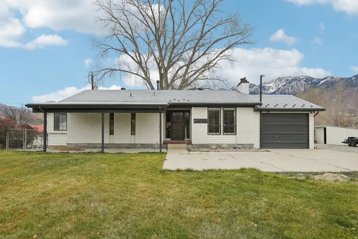 Ranch-style home with brick siding, a gate, a chimney, concrete driveway, and a garage