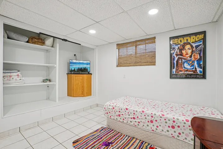 Bedroom featuring a drop ceiling, recessed lighting, and light tile patterned floors