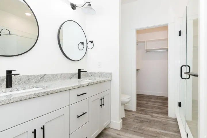 Bathroom with a spacious closet, double vanity, and light wood-style flooring