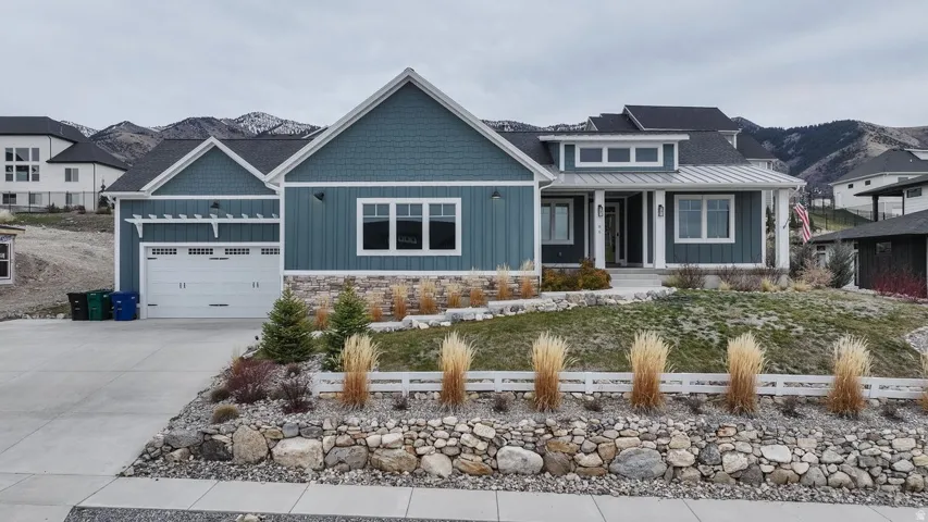 Craftsman-style home featuring covered porch, board and batten siding, driveway, stone siding, and a garage