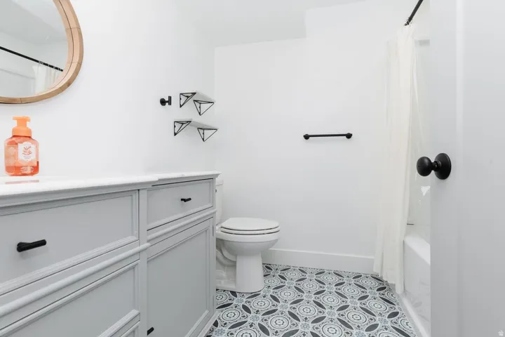Bathroom featuring shower / bath combination with curtain, vanity, and light tile patterned floors
