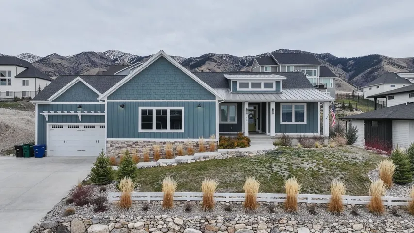 View of front facade with covered porch, driveway, board and batten siding, and a garage